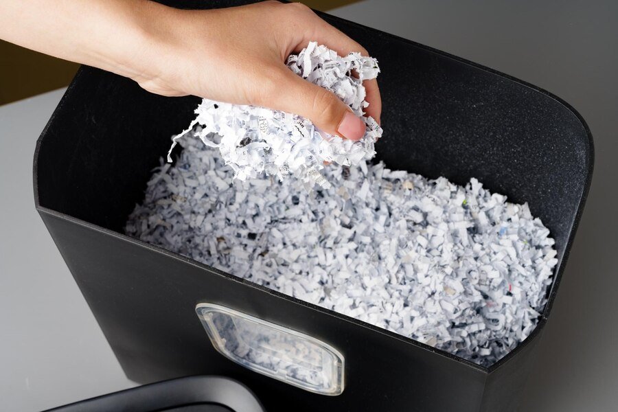 hand-using-paper-shredding-machine-against-gray-background_93675-160883